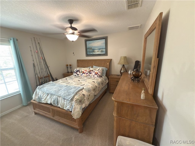 carpeted bedroom featuring visible vents, a textured ceiling, and multiple windows