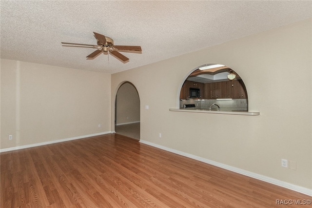 unfurnished room with hardwood / wood-style flooring, ceiling fan, and a textured ceiling