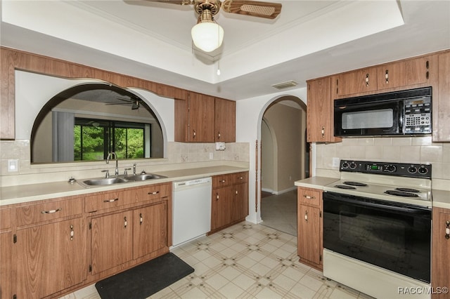 kitchen featuring tasteful backsplash, white appliances, a raised ceiling, crown molding, and sink