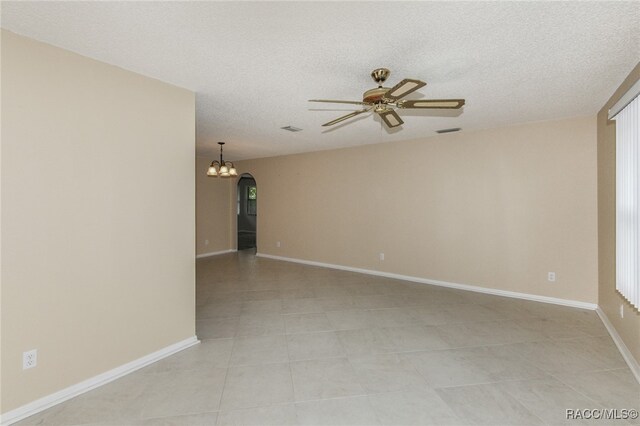 tiled empty room with ceiling fan with notable chandelier and a textured ceiling