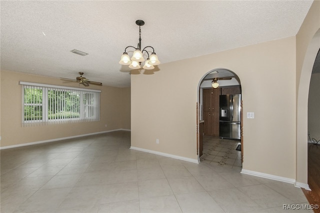 empty room with ceiling fan with notable chandelier and a textured ceiling