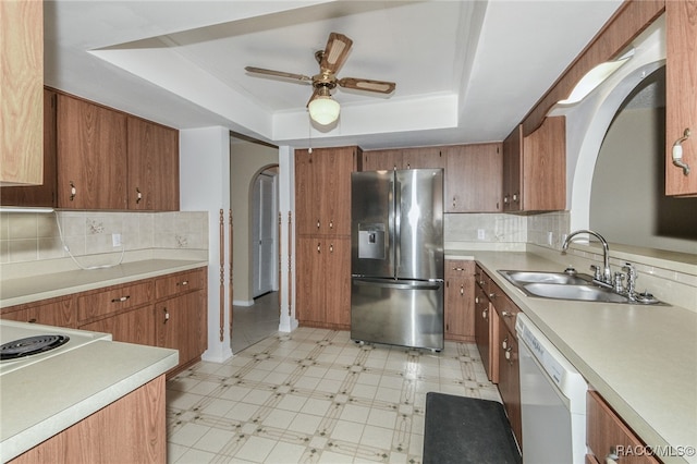 kitchen with stainless steel fridge, white dishwasher, a raised ceiling, ceiling fan, and sink