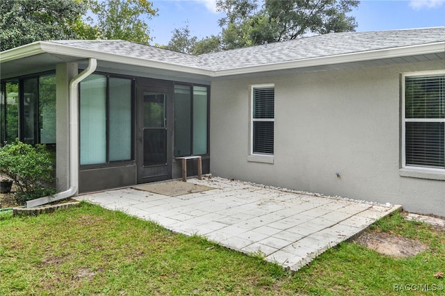 back of house featuring a lawn, a patio area, and a sunroom