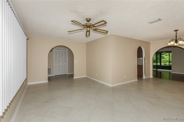 empty room featuring a textured ceiling, ceiling fan with notable chandelier, and light tile patterned floors