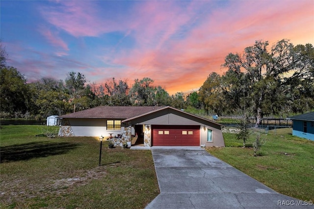 view of front of property with an attached garage, concrete driveway, stone siding, and a front yard