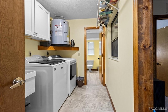 clothes washing area featuring a textured ceiling, electric water heater, baseboards, washer and dryer, and cabinet space