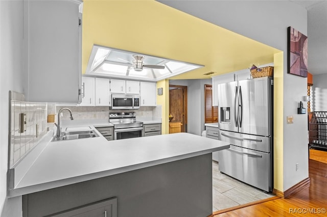 kitchen featuring ceiling fan, a sink, stainless steel appliances, light countertops, and backsplash