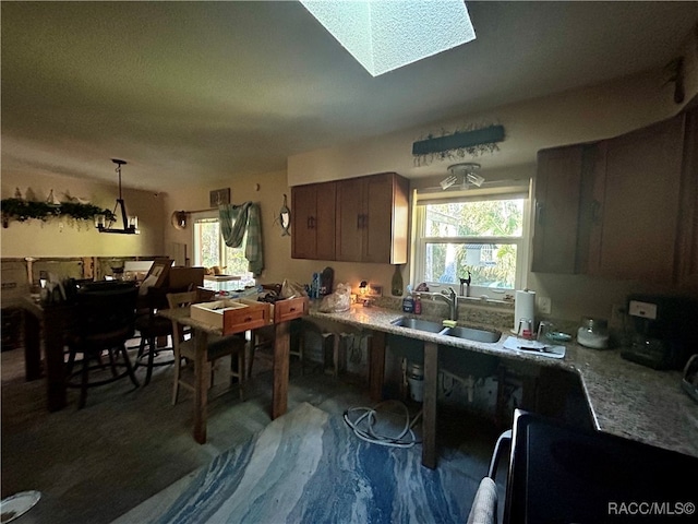 kitchen with decorative light fixtures, sink, and a skylight