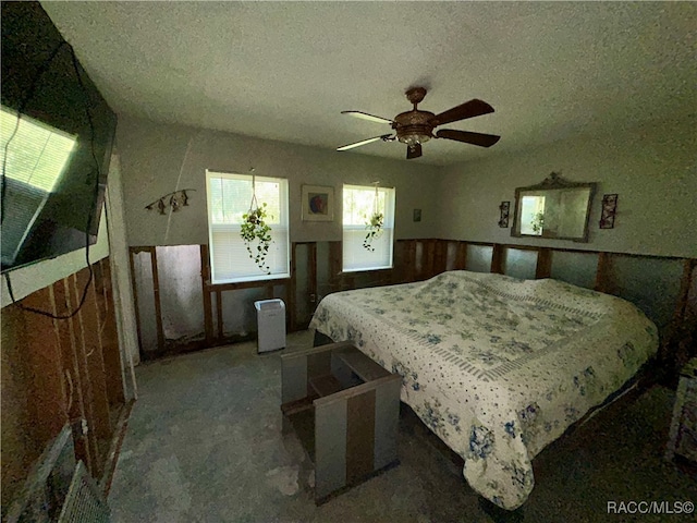 bedroom with a textured ceiling, dark carpet, and ceiling fan