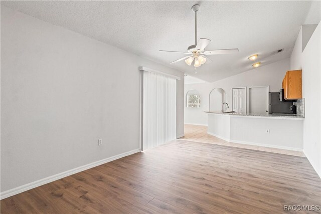 3143 Grayton Dr, Spring Hill, FL 34609 - unfurnished living room with ceiling fan, vaulted ceiling, light wood-style flooring, and a textured ceiling