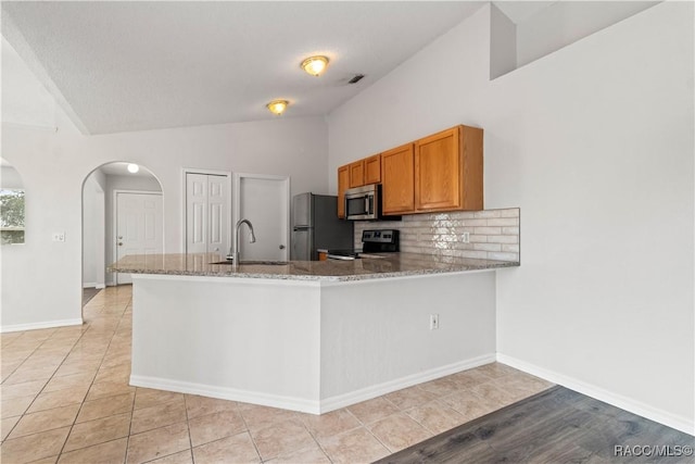 3143 Grayton Dr, Spring Hill, FL 34609 - kitchen with stainless steel microwave, electric stove, freestanding refrigerator, vaulted ceiling, and arched walkways