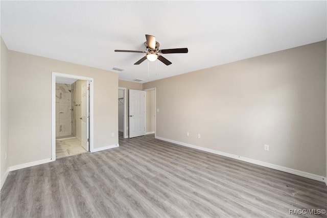 unfurnished bedroom featuring visible vents, ceiling fan, ensuite bath, wood finished floors, and baseboards