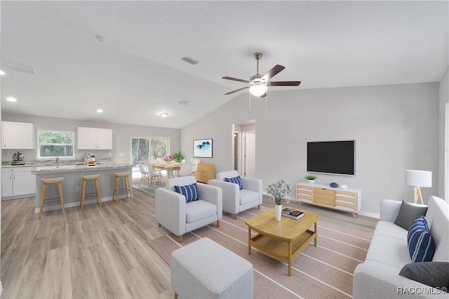 living room featuring baseboards, visible vents, lofted ceiling, light wood-type flooring, and recessed lighting