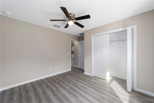 unfurnished bedroom featuring baseboards, visible vents, a ceiling fan, wood finished floors, and a closet