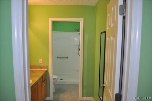 bathroom featuring vanity, tile patterned flooring, toilet, a textured ceiling, and walk in shower