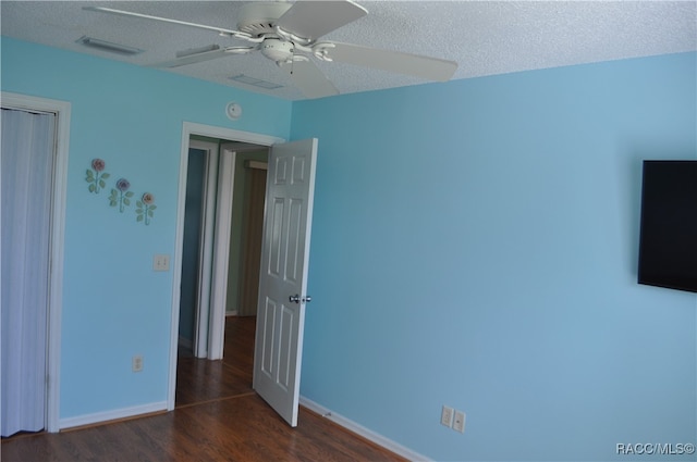 unfurnished bedroom with ceiling fan, dark hardwood / wood-style floors, and a textured ceiling