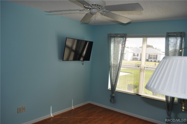 unfurnished room with ceiling fan, dark hardwood / wood-style flooring, and a textured ceiling