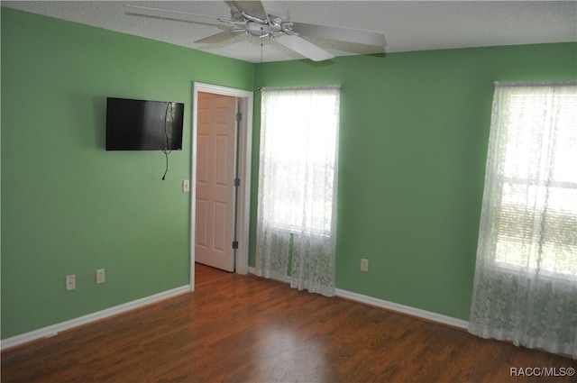 unfurnished room with ceiling fan, dark wood-type flooring, and a textured ceiling