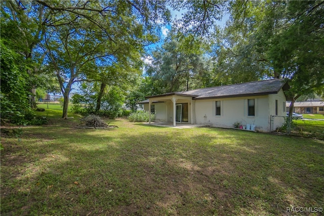 rear view of property with a lawn and a patio