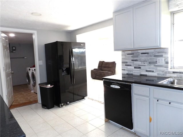 kitchen with light tile patterned flooring, white cabinets, decorative backsplash, washing machine and clothes dryer, and black appliances