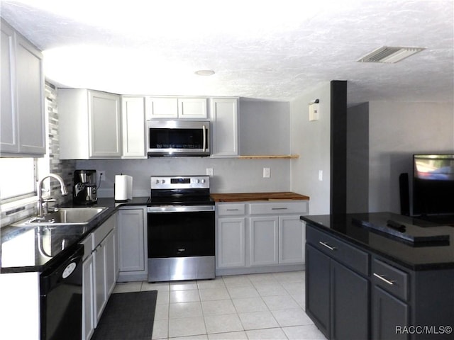 kitchen with sink, light tile patterned floors, appliances with stainless steel finishes, gray cabinetry, and a textured ceiling