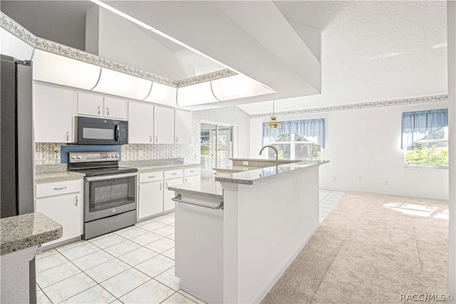 kitchen with white cabinets, decorative light fixtures, plenty of natural light, and electric stove