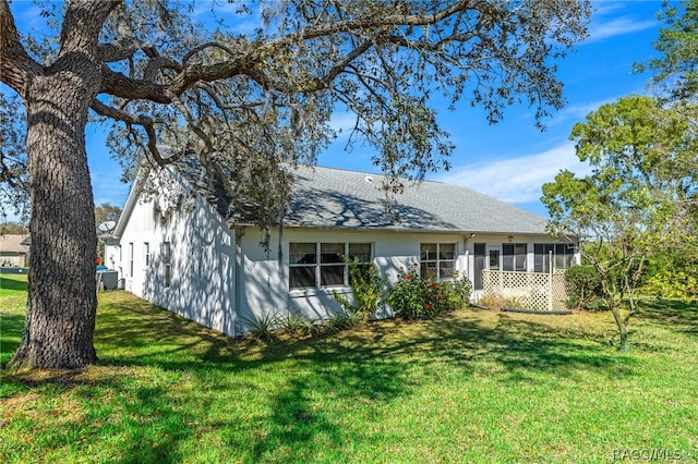 back of house featuring central AC, a sunroom, and a yard