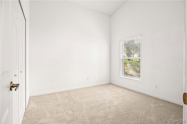 carpeted spare room featuring lofted ceiling