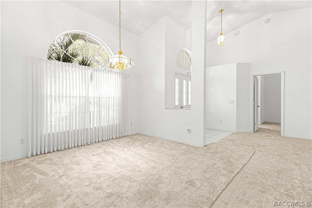 carpeted empty room featuring high vaulted ceiling and a notable chandelier