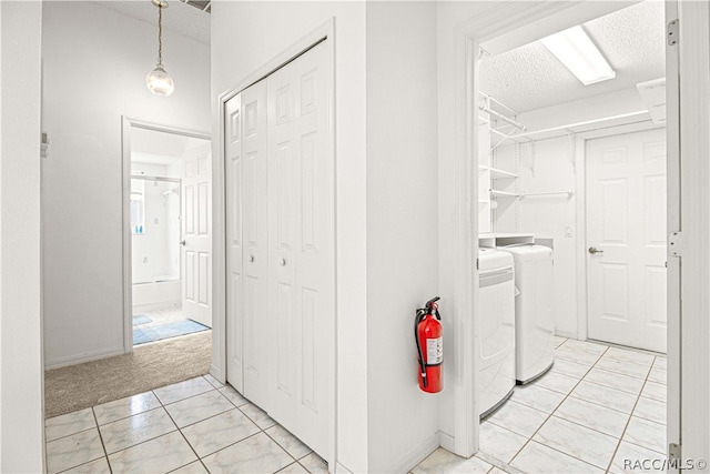 laundry area with washer and dryer, light carpet, and a textured ceiling