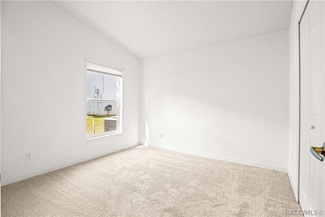 carpeted empty room featuring a textured ceiling and vaulted ceiling