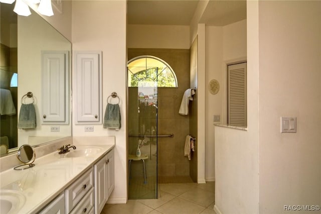 bathroom with tile patterned flooring, vanity, and tiled shower