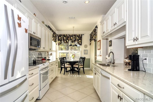 kitchen with white appliances, white cabinets, sink, light tile patterned floors, and decorative light fixtures