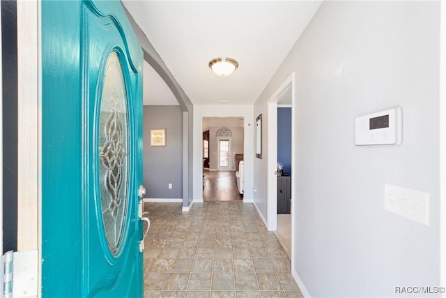 hall featuring arched walkways and baseboards