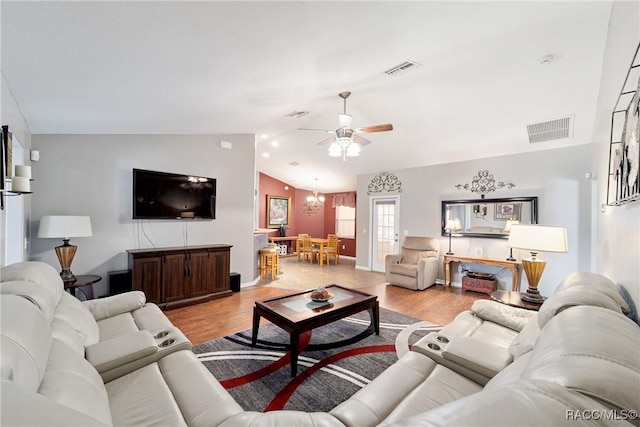 living area featuring lofted ceiling, light wood finished floors, visible vents, and ceiling fan with notable chandelier