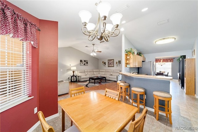 dining room with vaulted ceiling, ceiling fan with notable chandelier, baseboards, and light tile patterned floors
