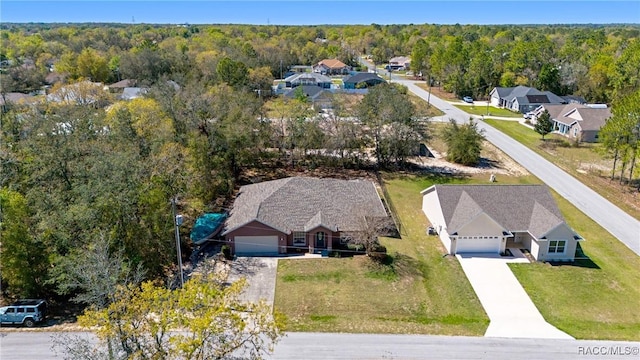 drone / aerial view featuring a wooded view and a residential view