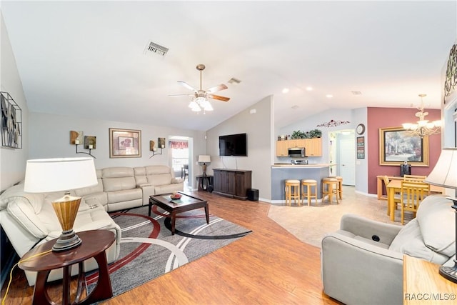 living area with light wood finished floors, ceiling fan with notable chandelier, visible vents, baseboards, and lofted ceiling