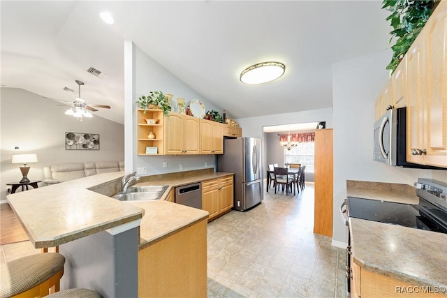 kitchen featuring a sink, a breakfast bar, light brown cabinetry, stainless steel appliances, and lofted ceiling