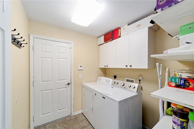 washroom featuring washing machine and clothes dryer, baseboards, and cabinet space