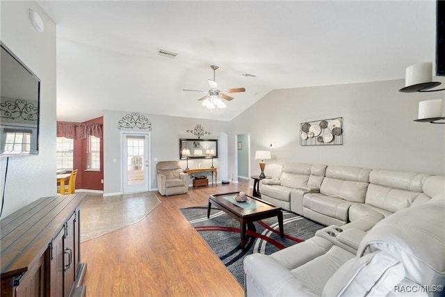 living room featuring a ceiling fan, visible vents, baseboards, light wood-style floors, and lofted ceiling