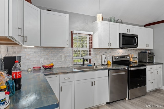 kitchen featuring decorative backsplash, appliances with stainless steel finishes, sink, light hardwood / wood-style flooring, and white cabinetry