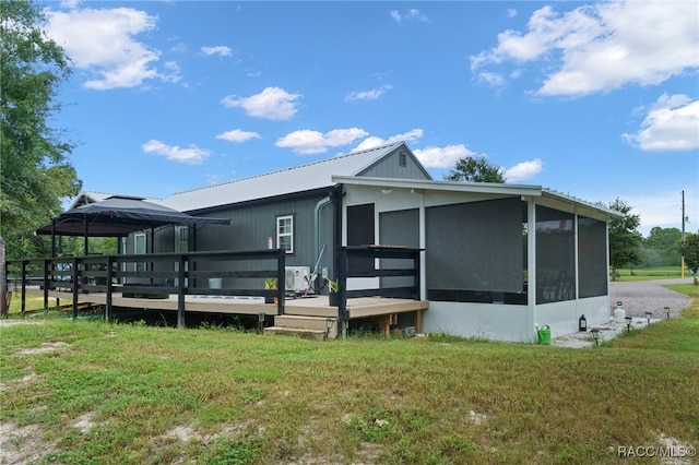 back of house featuring a gazebo, a deck, and a lawn