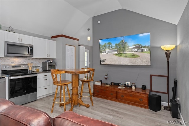 kitchen featuring lofted ceiling, light hardwood / wood-style flooring, appliances with stainless steel finishes, tasteful backsplash, and white cabinetry