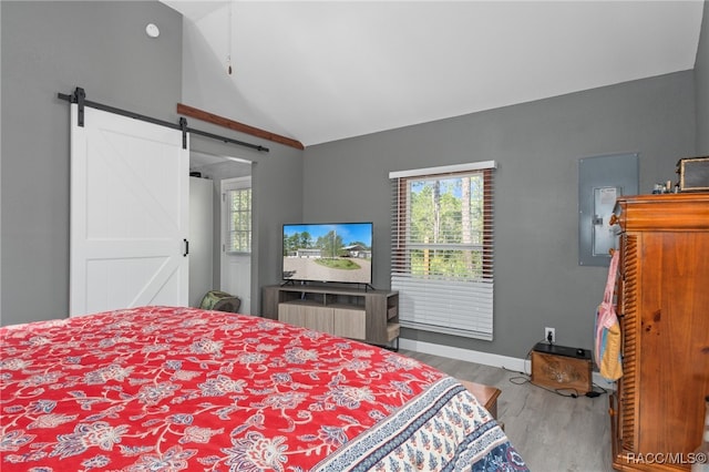 bedroom featuring a barn door, light hardwood / wood-style floors, and lofted ceiling