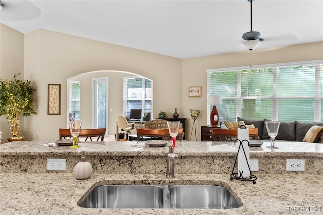 kitchen featuring ceiling fan and light stone countertops