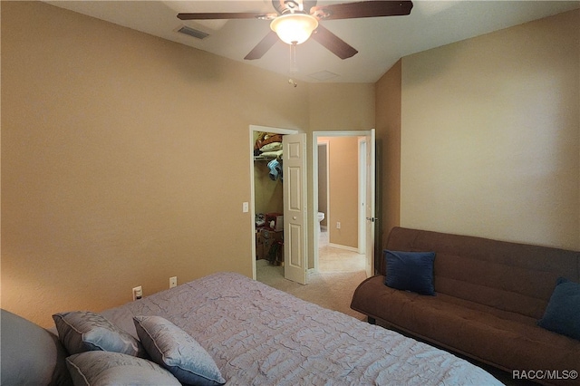 bedroom featuring ceiling fan, a walk in closet, light carpet, and a closet