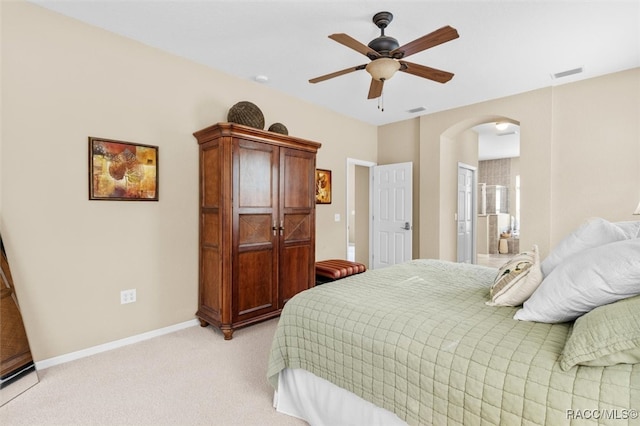 bedroom featuring ceiling fan, light carpet, and ensuite bath