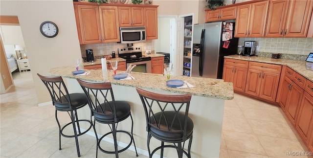 kitchen featuring a kitchen breakfast bar, light tile patterned floors, and appliances with stainless steel finishes