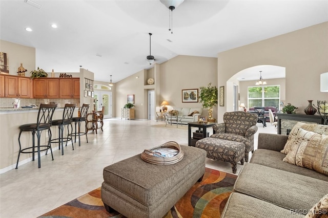 living room featuring light tile patterned floors, high vaulted ceiling, and ceiling fan with notable chandelier